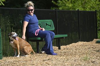 a woman sits on a bench with her dog at Beckington, Leland